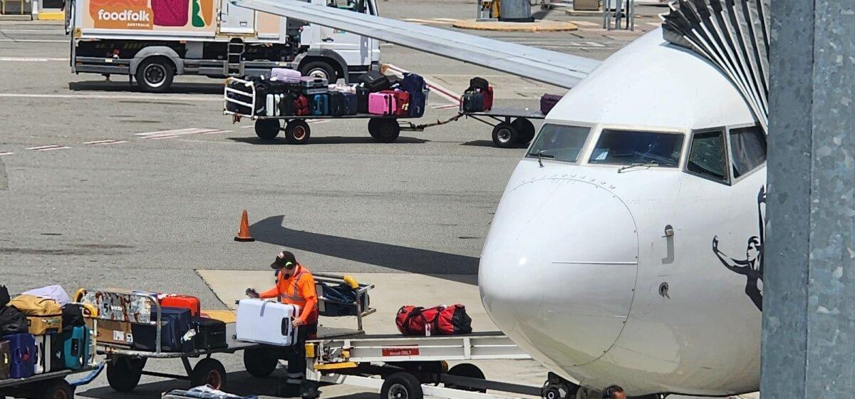 A baggage handler can be seen loading a suitcase onto a plane at Perth Airport, Australia, on Oct. 26, 2023. (Susan Mortimer/The Epoch Times)
