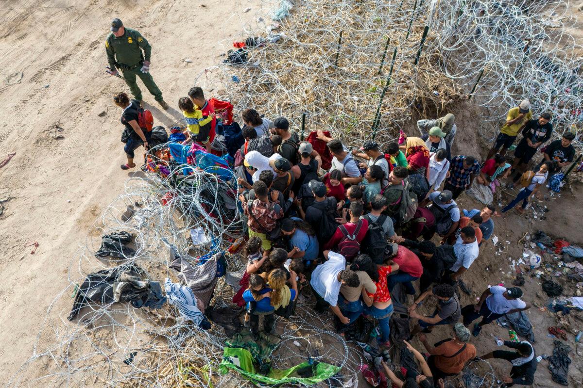 As seen from an aerial view a U.S. Border Patrol agent watches as illegal immigrants walk into the United States after crossing the Rio Grande from Mexico, in Eagle Pass, Texas, on Sept. 30, 2023. (John Moore/Getty Images)