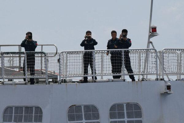 This photo taken on Sept. 22, 2023, shows Chinese coast guard personnel aboard their ship recording photo and footage as a Philippine Bureau of Fisheries and Aquatic Resources (BFAR) ship sails near the Chinese-controlled Scarborough Shoal in waters of the disputed South China Sea. (Ted Aljibe/AFP via Getty Images)