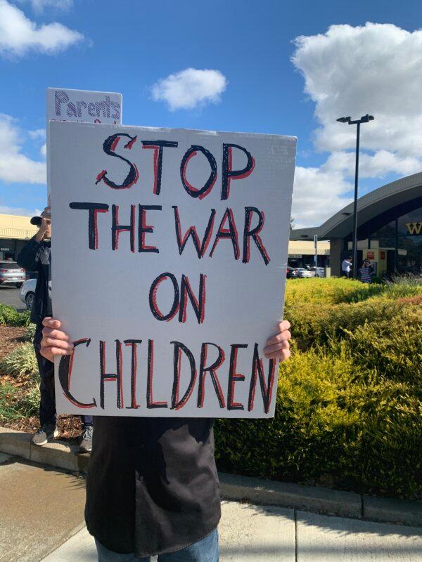 A protestor holds a sign at the Worldwide Stop the War on Children Rally in Castro Valley, Calif., on Oct. 21, 2023. (Helen Billings/The Epoch Times)