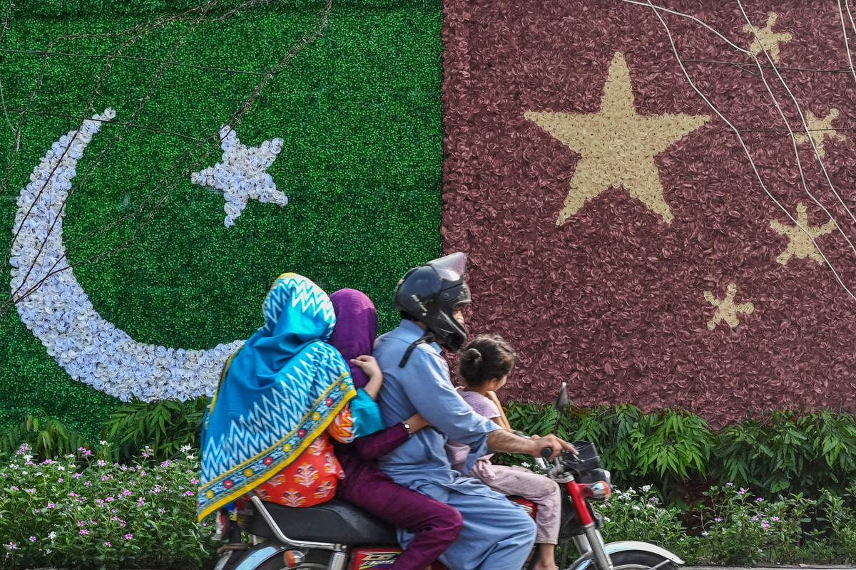  A family rides past a decoration depicting the national flags of China and Pakistan ahead of the visit of Chinese Vice Premier He Lifeng, in Lahore, Pakistan, on July 30, 2023. (Arif Ali/AFP via Getty Images)