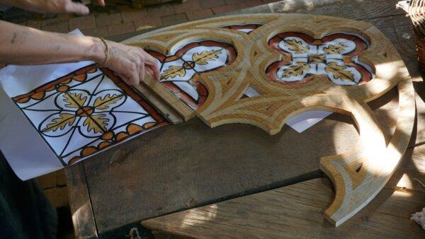 Installing painted linen windows into the tracery stone framework. Tracery is a decorative method of providing the stone framework to place wooden frames in, and the support needed for the chapel windows in the Guédelon chapel. (Copyright Guédelon)