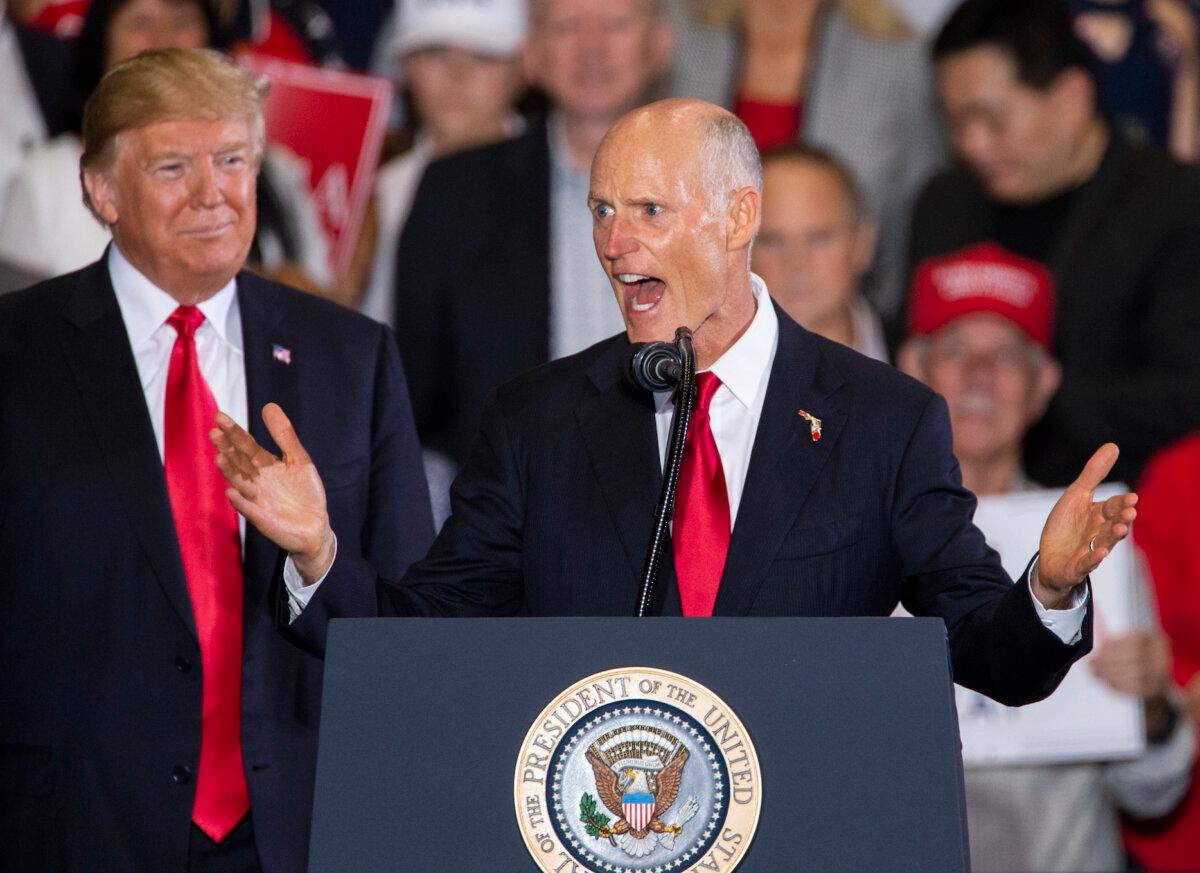 Then-Florida governor Rick Scott speaks with then-President Donald Trump at a campaign rally at the Pensacola International Airport in Pensacola, Florida, on Nov. 3, 2018. (Mark Wallheiser/Getty Images)