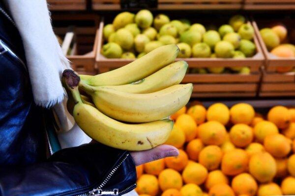 A customer holds bananas in front of a fruit shelf in an organic supermarket in Saintes, western France, on Oct. 23, 2018. (Georges Gobet/AFP via Getty Images)