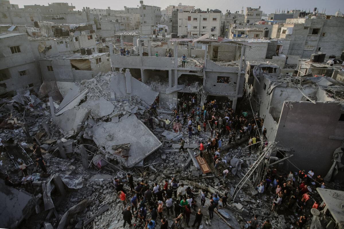 Palestinian civilians and rescue teams sift through the debris of a collapsed building in Al-Maghazi, located in the central Gaza Strip, in search of survivors and victims following the Israeli bombardment on Nov. 5, 2023. (Mohammed Zaanoun/Middle East Images/AFP via Getty Images)