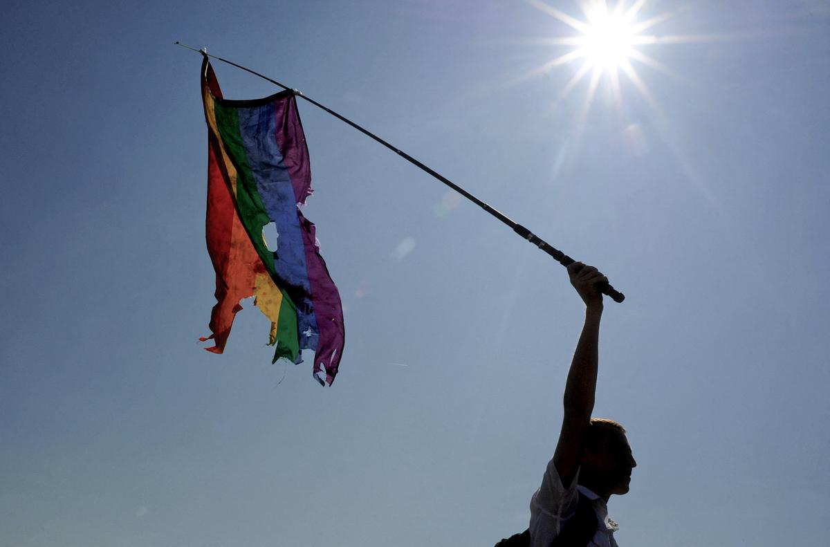 A person waves a damaged rainbow flag during a gay pride event in St. Petersburg, Russia, on July 26, 2014. (OLGA MALTSEVA/AFP via Getty Images)