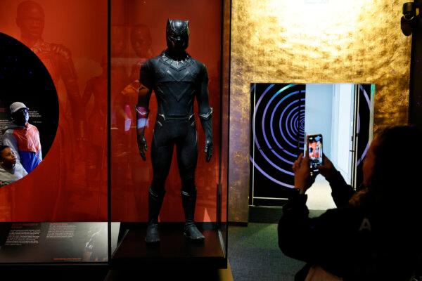 Visitors look at the costume worn by actor Chadwick Boseman when he performed the title character in the 2018 film Black Panther at the temporary exhibit "Afrofuturism: A History of Black Futures" at the Smithsonian National Museum of African American History and Culture in Washington on March 24, 2023. The exhibit assembles more than 100 objects from music, film, television, comic books, fashion, theater, literature, and more that covers more than a century of Afrofuturism. (Chip Somodevilla/Getty Images)