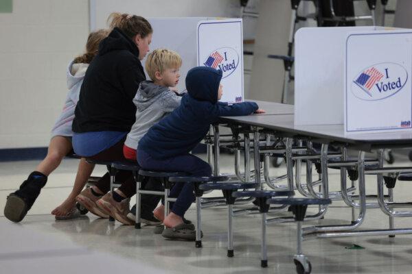 A voter casts her ballot accompanied by three children at Haymarket Elementary School in Haymarket, Va., on Nov. 7, 2023. (Win McNamee/Getty Images)