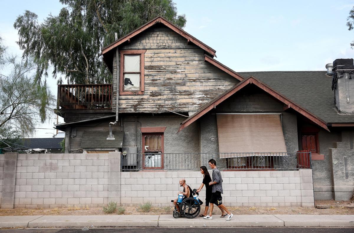 People pass a rundown property on their way to a market in Phoenix on July 24, 2023. (Mario Tama/Getty Images)