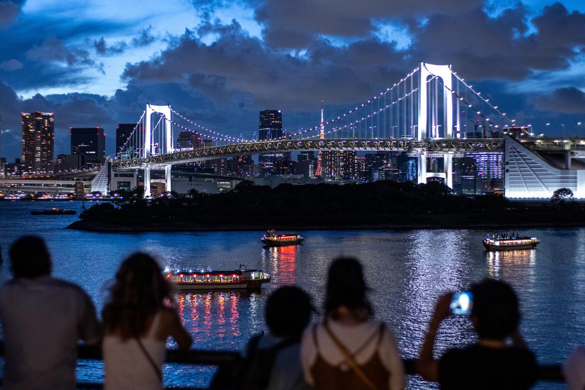 People visit Odaiba Marine Park, as the Rainbow Bridge is seen in the background in Tokyo, Japan, on August 26, 2023. (Philip Fong/AFP via Getty Images)