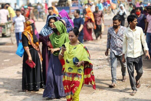 A female garment worker uses cellphone while coming out of a factory during lunch hours at the Ashulia area, outskirts of Dhaka, Bangladesh, on Nov. 8, 2023. (Mohammad Ponir Hossain/Reuters)