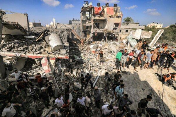 People gather by the rubble of a building that collapsed after Israeli bombardment while searching for survivors and the bodies of victims, in Khan Yunis in the southern Gaza Strip on Nov. 8, 2023. (Mahmud Hams/AFP via Getty Images)
