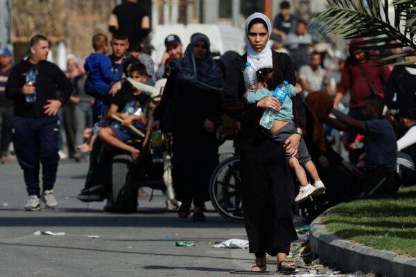 A woman carries a child as Palestinians fleeing north Gaza walk towards the south in the central Gaza Strip, on Nov. 9, 2023. (Mohammed Salem/Reuters)