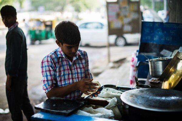 An Indian vendor prepares a popular Indian dish called paratha on a gas stove attached to his older brother's bicycle at a transport stand in a street of New Delhi on May 19, 2016. (Roberto Schmidt/AFP via Getty Images)