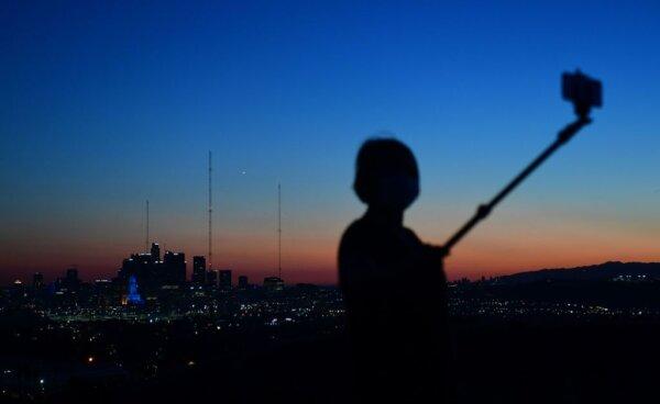 A selfie-stick is used for cellphone photos after sunset in Los Angeles, Calif., on April 24, 2020. (Frederic J. Brown/AFP via Getty Images)