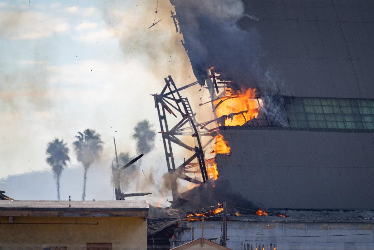 A fire continues to burn down a historic blimp hangar in Tustin, Calif., on Nov. 14, 2023. (John Fredricks/The Epoch Times)