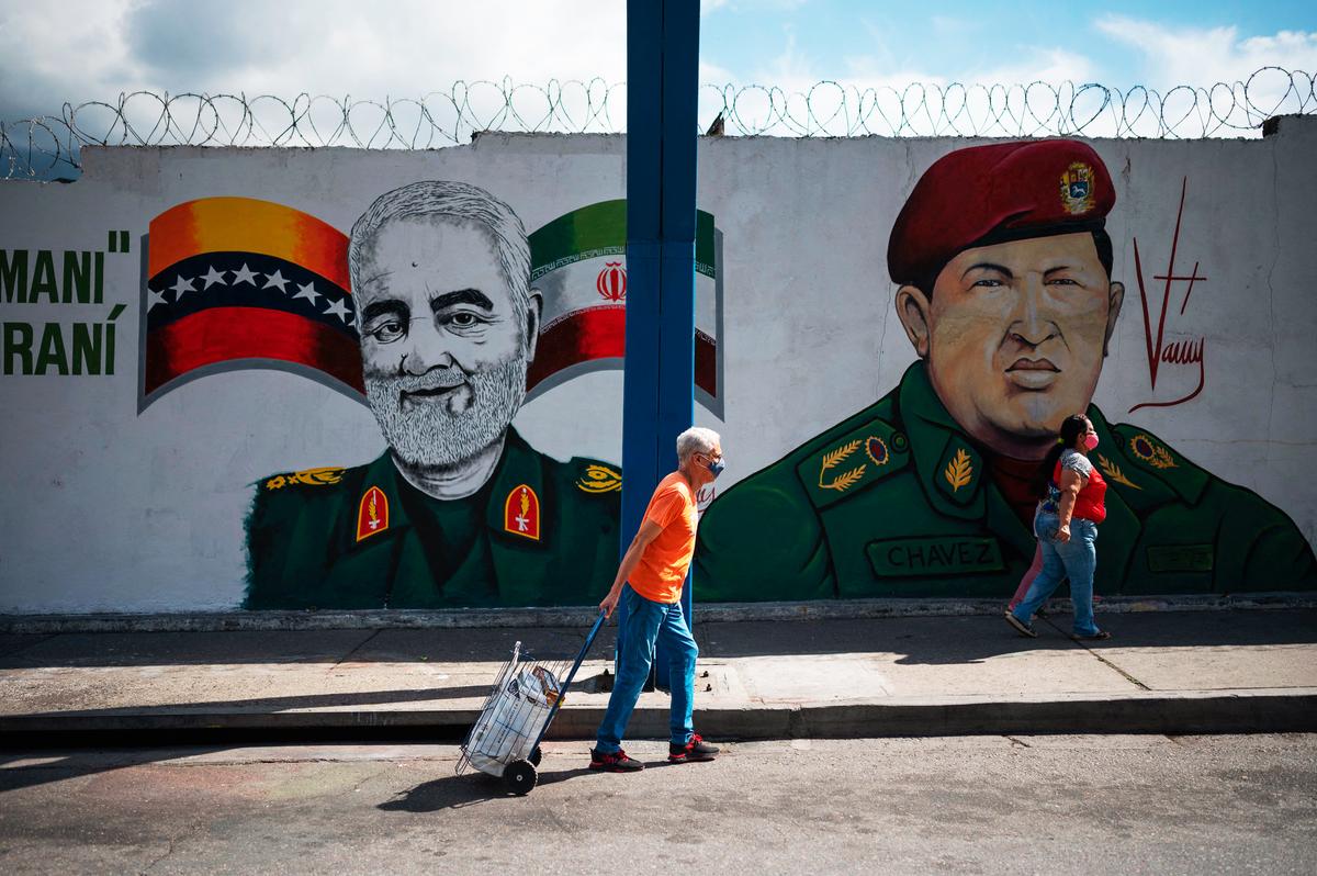 People walk by a mural depicting slain Iranian general Qasem Soleimani (L) alongside Venezuelan President Hugo Chávez (R), in Caracas, Venezuela, on Jan. 4, 2023. (FEDERICO PARRA/AFP via Getty Images)