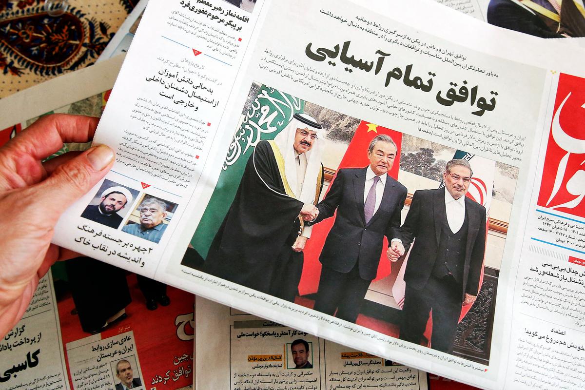 A man in Tehran holds a local newspaper reporting on the China-brokered deal between Iran and Saudi Arabia to restore ties, signed in Beijing the previous day, on March 11, 2023. (ATTA KENARE/AFP via Getty Images)