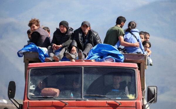 Refugees from Nagorno-Karabakh ride in a truck upon their arrival at the border village of Kornidzor, Armenia, on Sept. 27, 2023. (Irakli Gedenidze/Reuters)