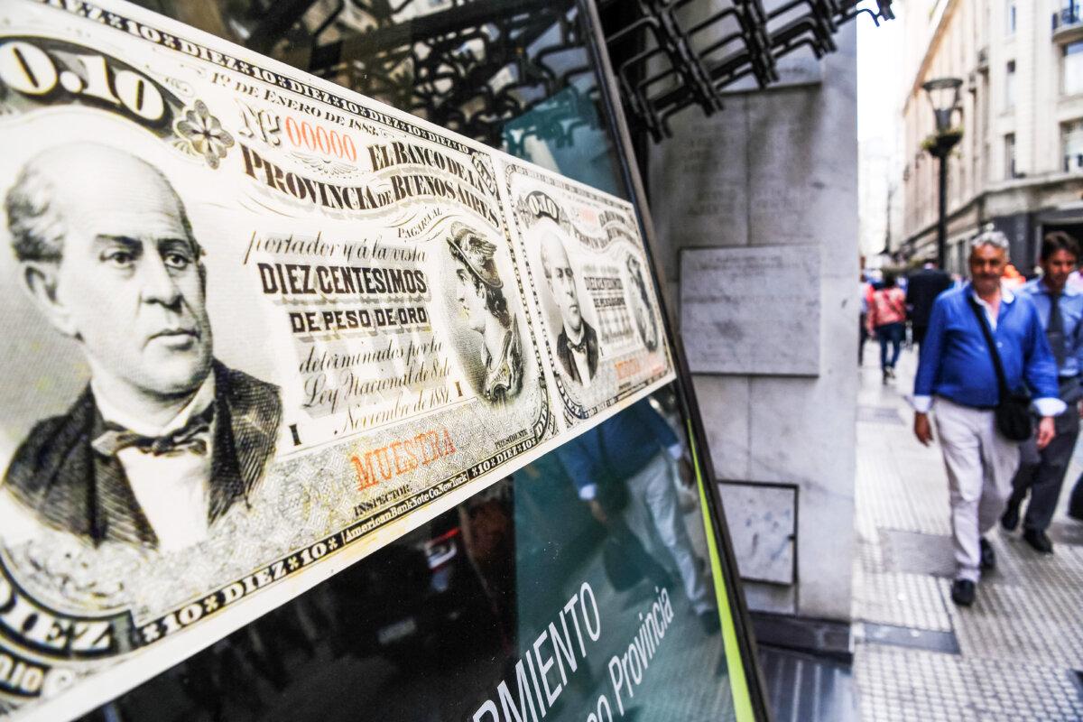 People walk past a bank branch decorated with images of old Argentine peso bills, in Buenos Aires, Argentina, on Sept. 26, 2018. Argentina’s year on year inflation hit a staggering 142 percent during election week. (Eitan Abramovich/AFP via Getty Images)