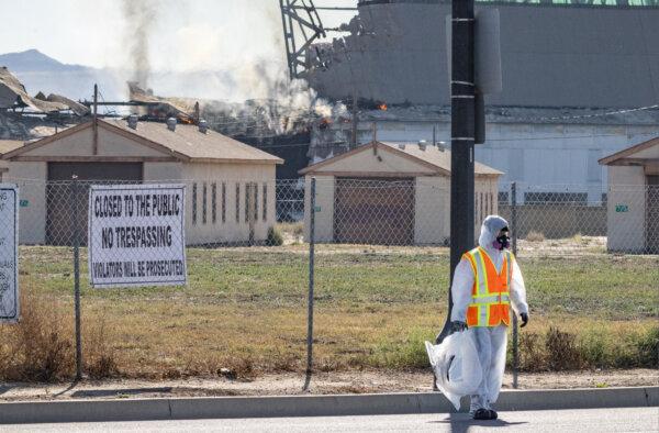 Men search for hazardous materials as a fire continues to burn inside a historic blimp hangar in Tustin, Calif., on Nov. 14, 2023. (John Fredricks/The Epoch times)