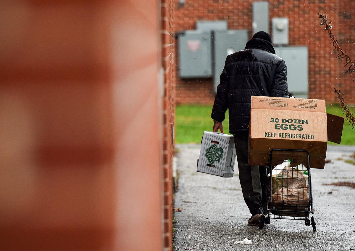People carry food donated by volunteers from the Baltimore Hunger Project outside of Padonia International Elementary school in Cockeysville, Md., on Dec. 4, 2020. (OLIVIER DOULIERY/AFP via Getty Images)