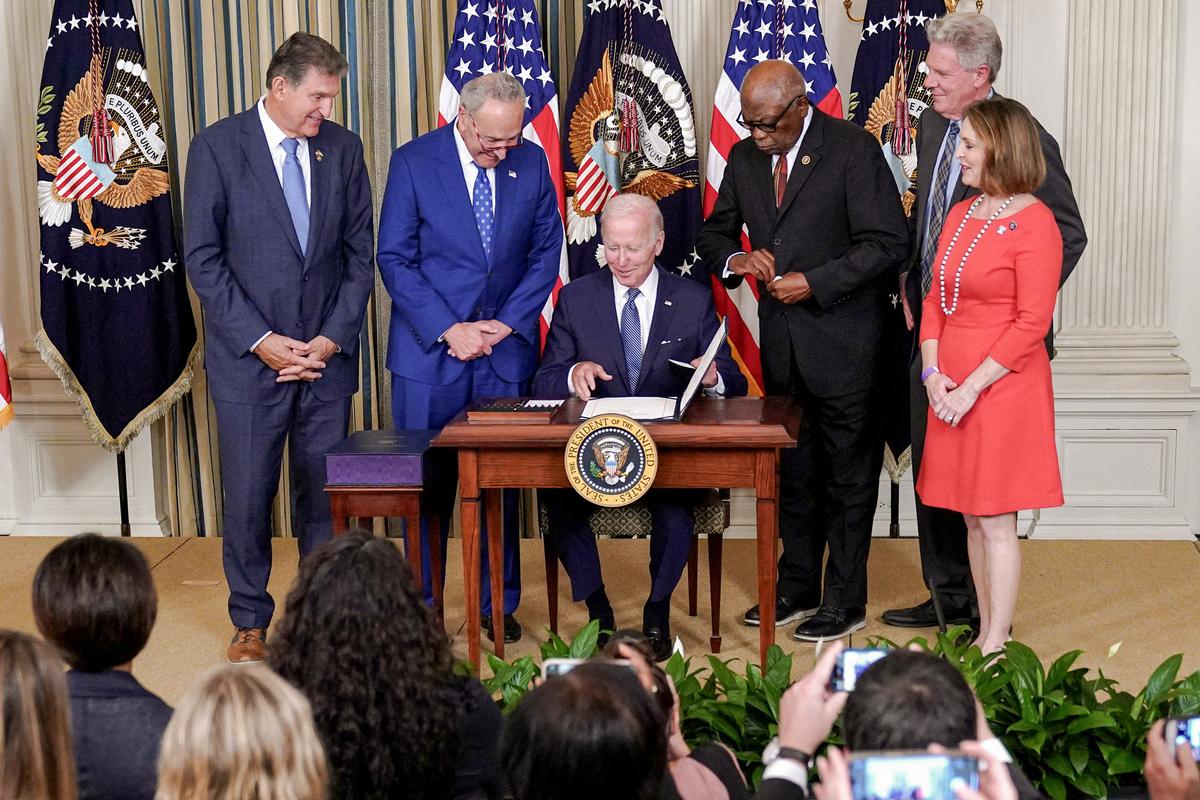 President Joe Biden (C), flanked by lawmakers, smiles after signing the Inflation Reduction Act of 2022, in the White House in Washington on Aug. 16, 2022. (MANDEL NGAN/AFP via Getty Images