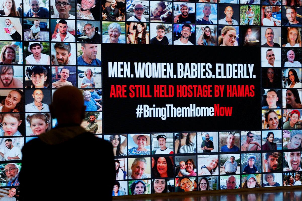 A person stands in front of pictures during a demonstration to demand the liberation of hostages who are being held in the Gaza Strip after they were seized by Hamas terrorists on Oct. 7, in Tel Aviv, Israel, on Nov. 21, 2023. (Amir Cohen/Reuters)