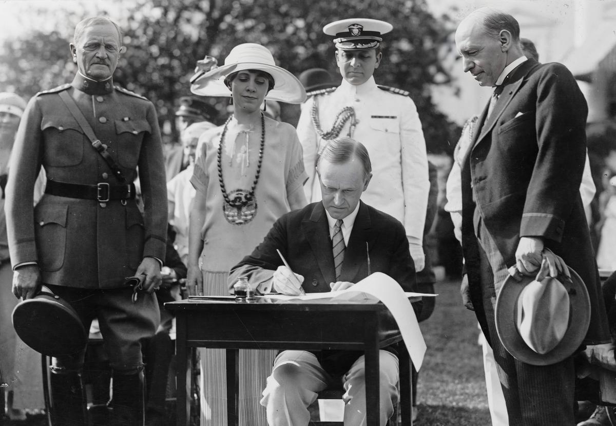 President Calvin Coolidge signs a bill to funding the Veterans Bureau, at the White House in Washington on June 5, 1924. (Public Domain)