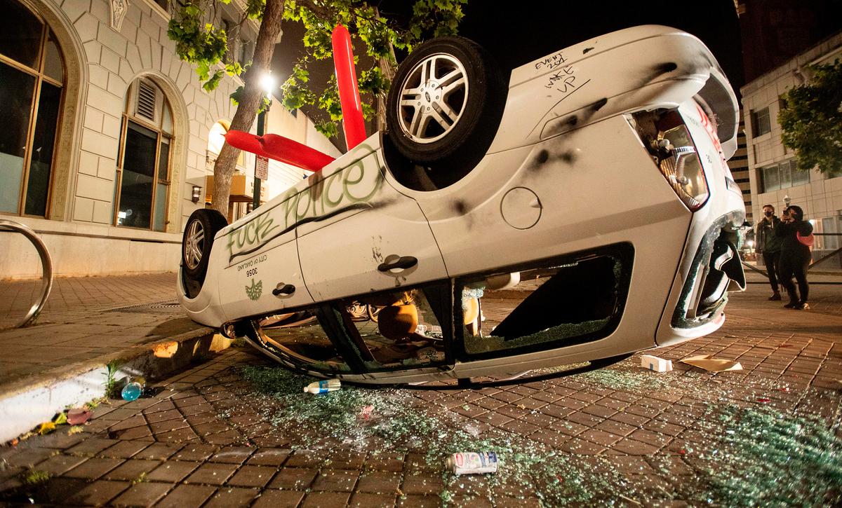  A vandalized car is flipped upside down as protesters face off against police in Oakland, Calif., on May 29, 2020. (JOSH EDELSON/AFP via Getty Images)