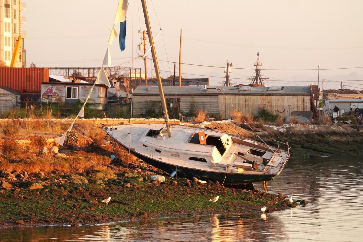  An abandoned, derelict sailboat lies stranded along the shoreline of the Oakland Estuary on Nov. 13, 2023. (Allan Stein/The Epoch Times)