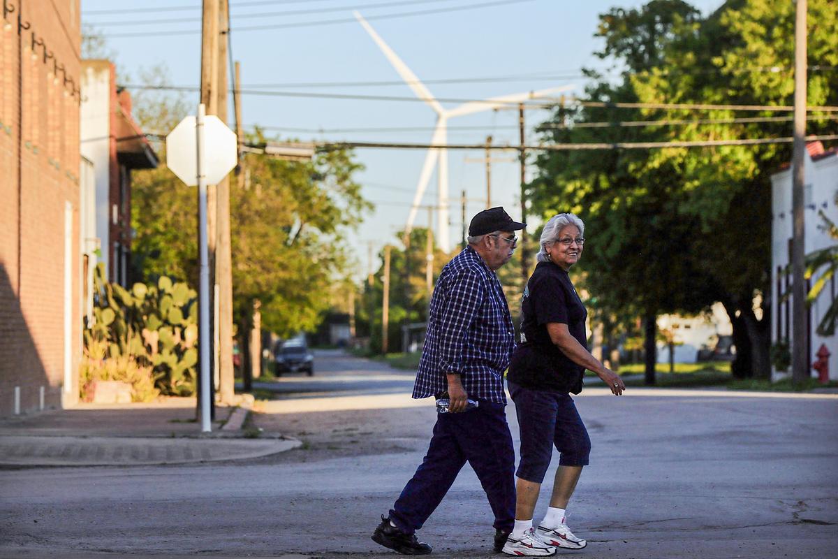 A wind turbine is seen in the background as a couple crosses a street in Taft, Texas, on March 27, 2015. (Spencer Platt/Getty Images)