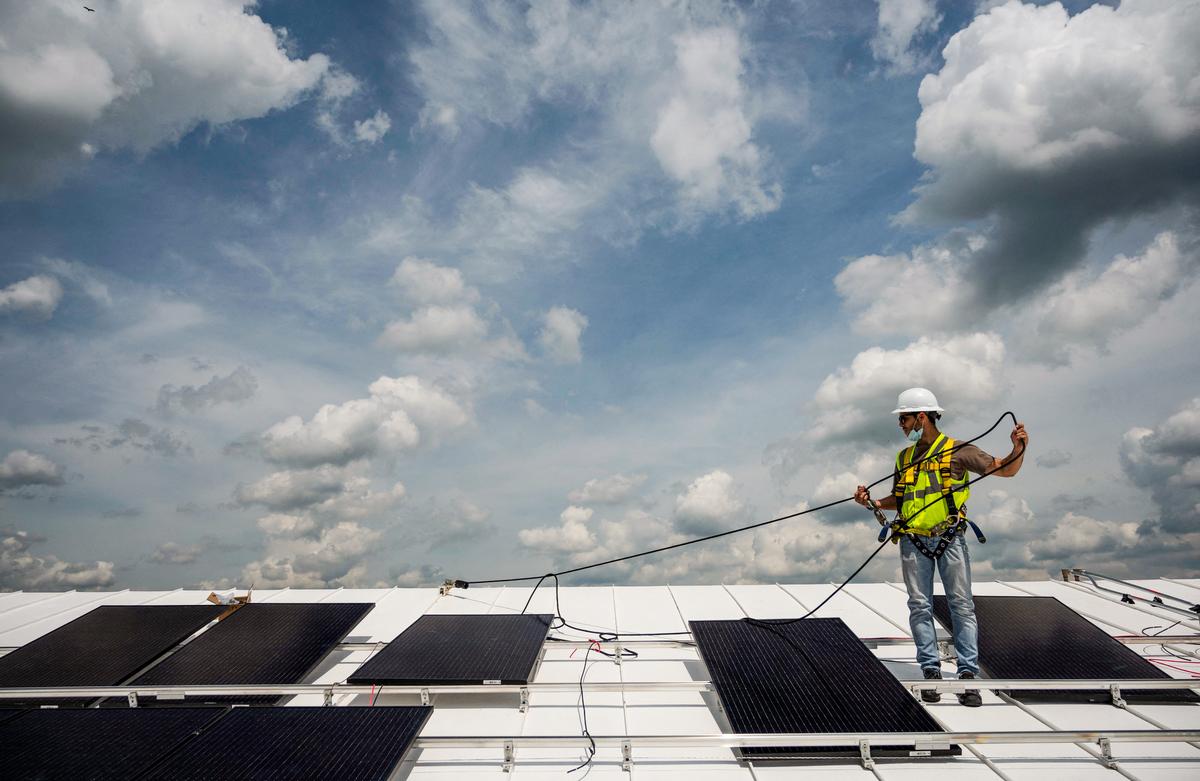 A man installs solar panels on the roof of a church in Alexandria, Va., on May 17, 2021. (Andrew Caballero-Reynolds/AFP via Getty Images)