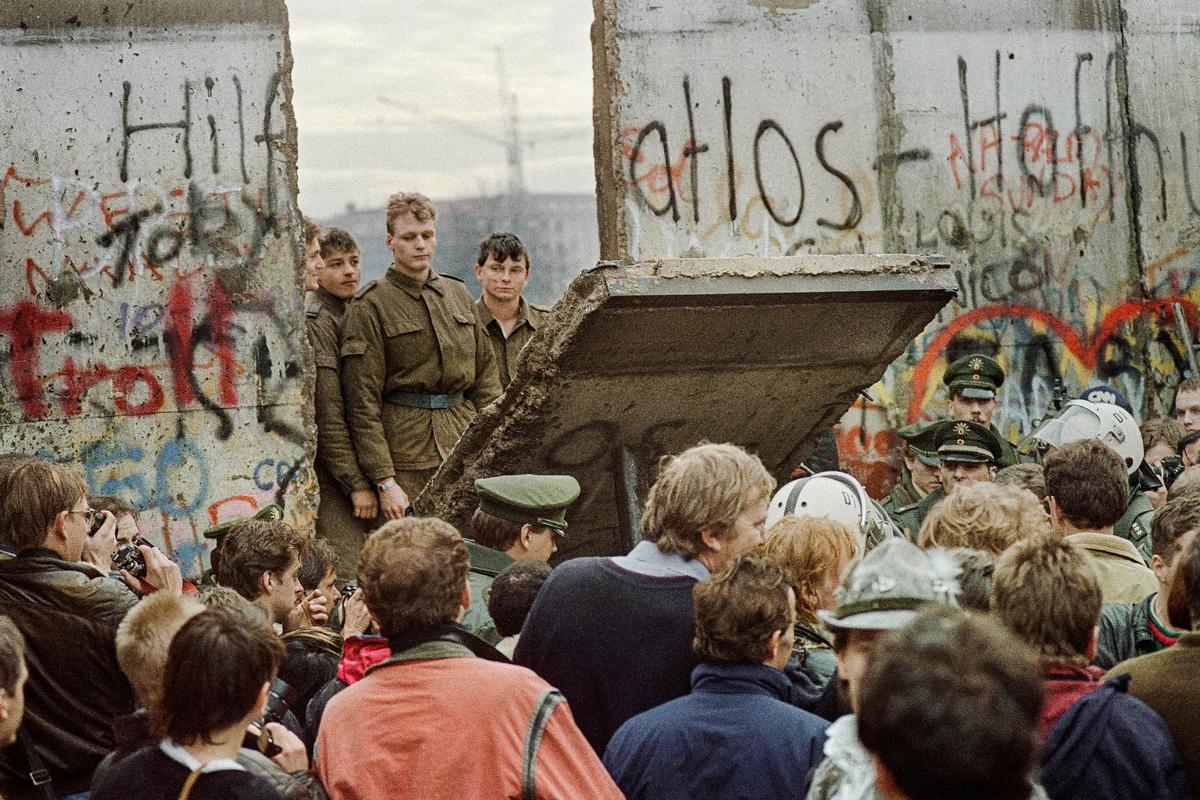 West Berliners crowd in front of the Berlin Wall early on Nov. 11, 1989, as they watch East German border guards demolishing a section of the wall. (Gerard Malie/AFP via Getty Images)