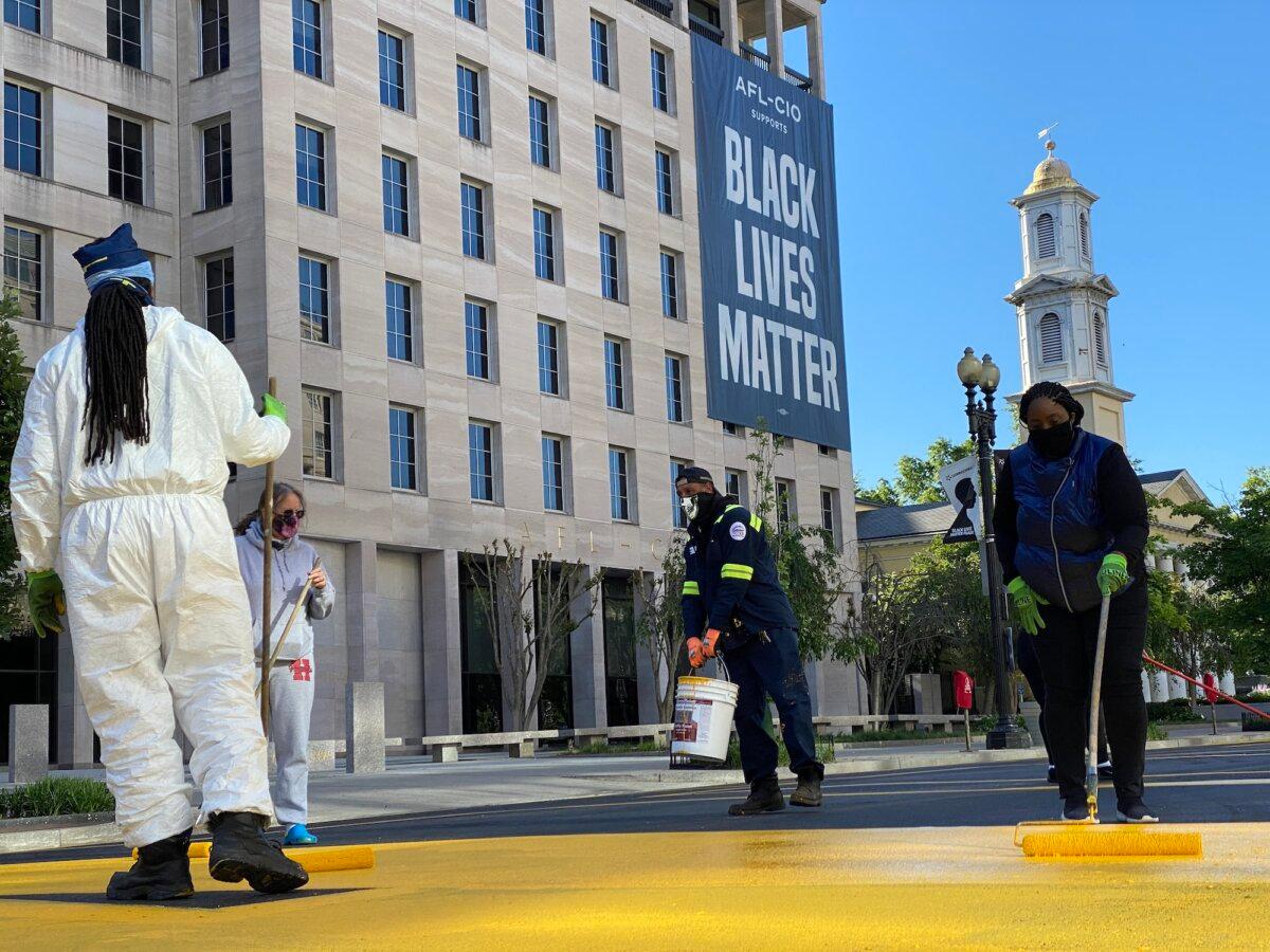 Volunteers add a new coat of paint to the Black Lives Matter sign that runs two city blocks near the White House, on what was part of 16th Street but was renamed Black Lives Matter Plaza, in Washington, on May 13, 2021. (Eric Baradat/AFP/Getty Images)