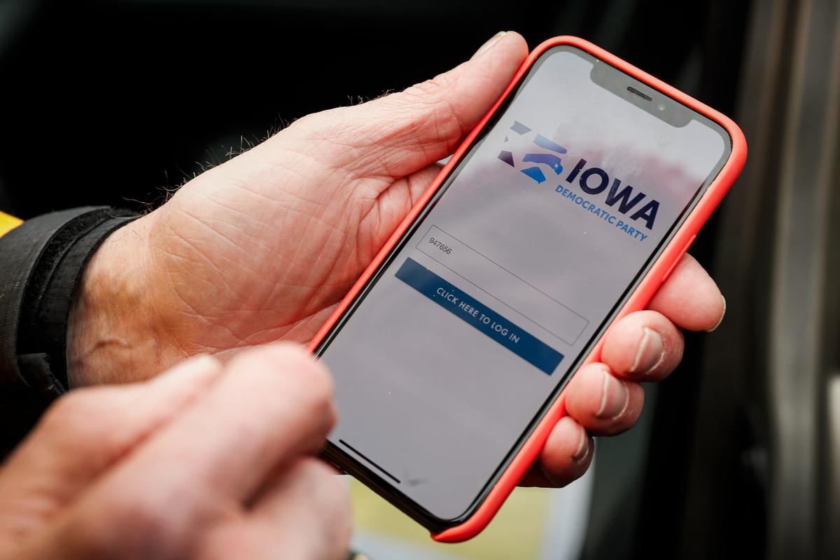 Precinct captain Carl Voss, of Des Moines, Iowa, holds his iPhone that shows the Iowa Democratic Party's caucus reporting app, in Des Moines, Iowa, on Feb. 4, 2020. (Charlie Neibergall/AP Photo)
