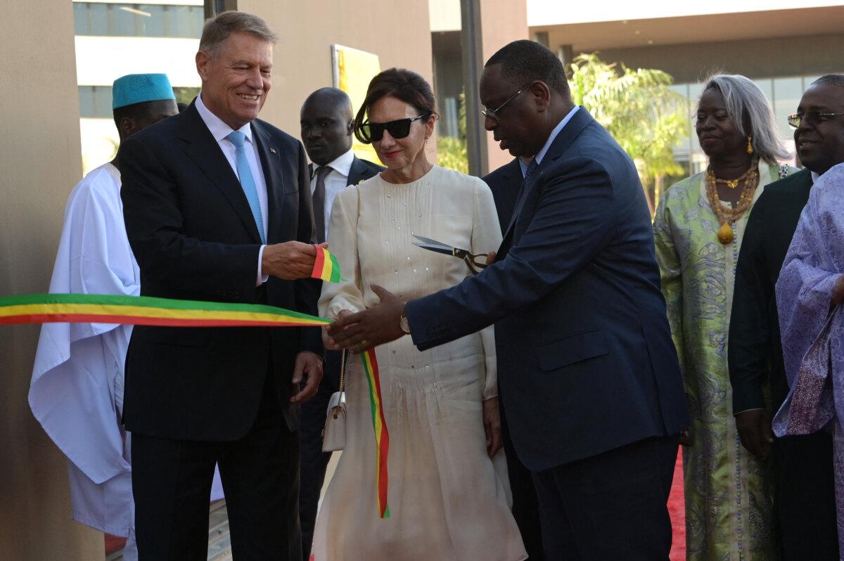 (L–R) Romanian President Klaus Iohannis, First Lady Carmen Iohannis, and Senegalese President Macky Sall cut a ribbon during the inauguration of a new regional headquarters for the United Nations in Diamniadio, Senegal, on Nov.23, 2023. (Seyllou/AFP via Getty Images)