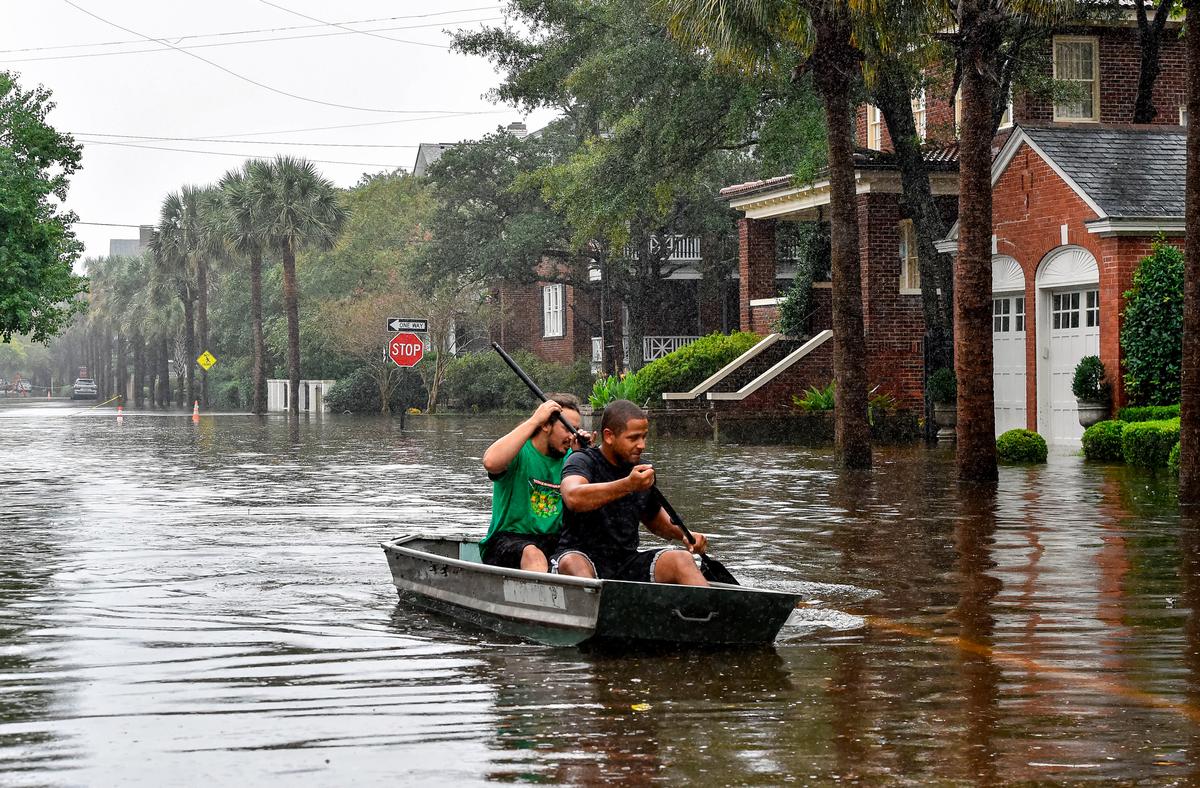  Two men row a boat on a flooded street in Charleston, S.S., on Oct. 4, 2015. Voters indicated that solving flooding issues was an important topic during the 2023 mayoral election. (MLADEN ANTONOV/AFP via Getty Images)
