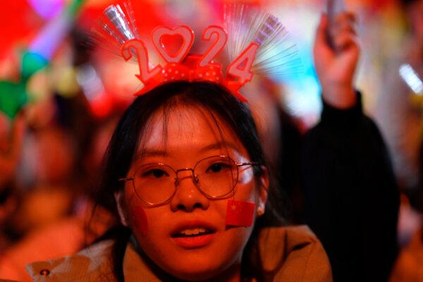  A reveller wearing a 2024 headband looks on during a New Year countdown event in Beijing on Dec. 31, 2023. (PEDRO PARDO/AFP via Getty Images)