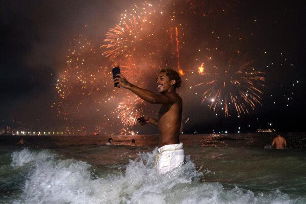  A man holds up his mobile phone as he watches the traditional New Year's fireworks from the water at Copacabana Beach in Rio de Janeiro, Brazil, on Jan. 1, 2024. (TERCIO TEIXEIRA/AFP via Getty Images)