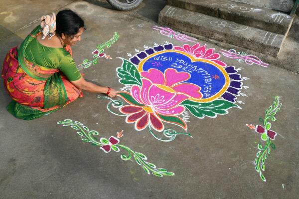  A woman applies coloured powder to a "rangoli" design to usher in the new year in front of a home in Hyderabad, India, on Jan. 1, 2024. (Noah SEELAM/AFP)