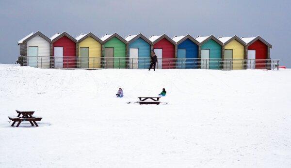 People ride sledges besides the beach huts at Blyth in Northumberland, North East England, on Dec. 3, 2023. (Owen Humphreys/PA Wire)