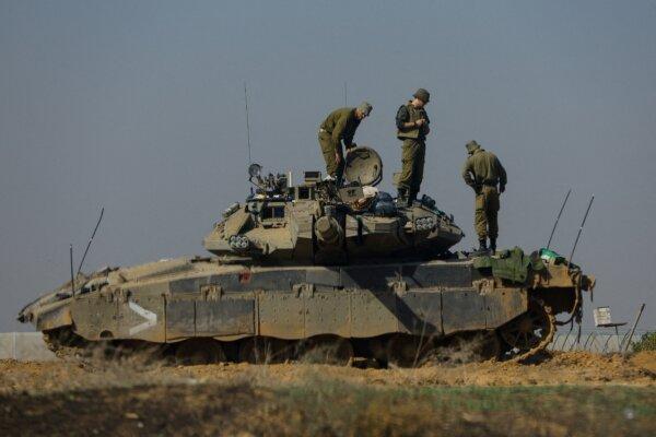 Israeli soldiers work on a tank near the border with Gaza, as seen from southern Israel, on Dec. 3, 2023. (Alexander Ermochenko/Reuters)