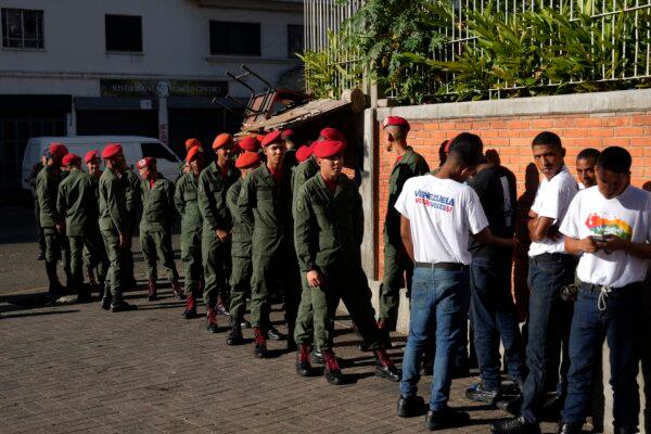 Soldiers wait in line to vote for on a referendum about the future of a disputed territory with Guyana, at a polling station in Caracas, Venezuela, on Dec. 3, 2023. (AP Photo/Ariana Cubillos)