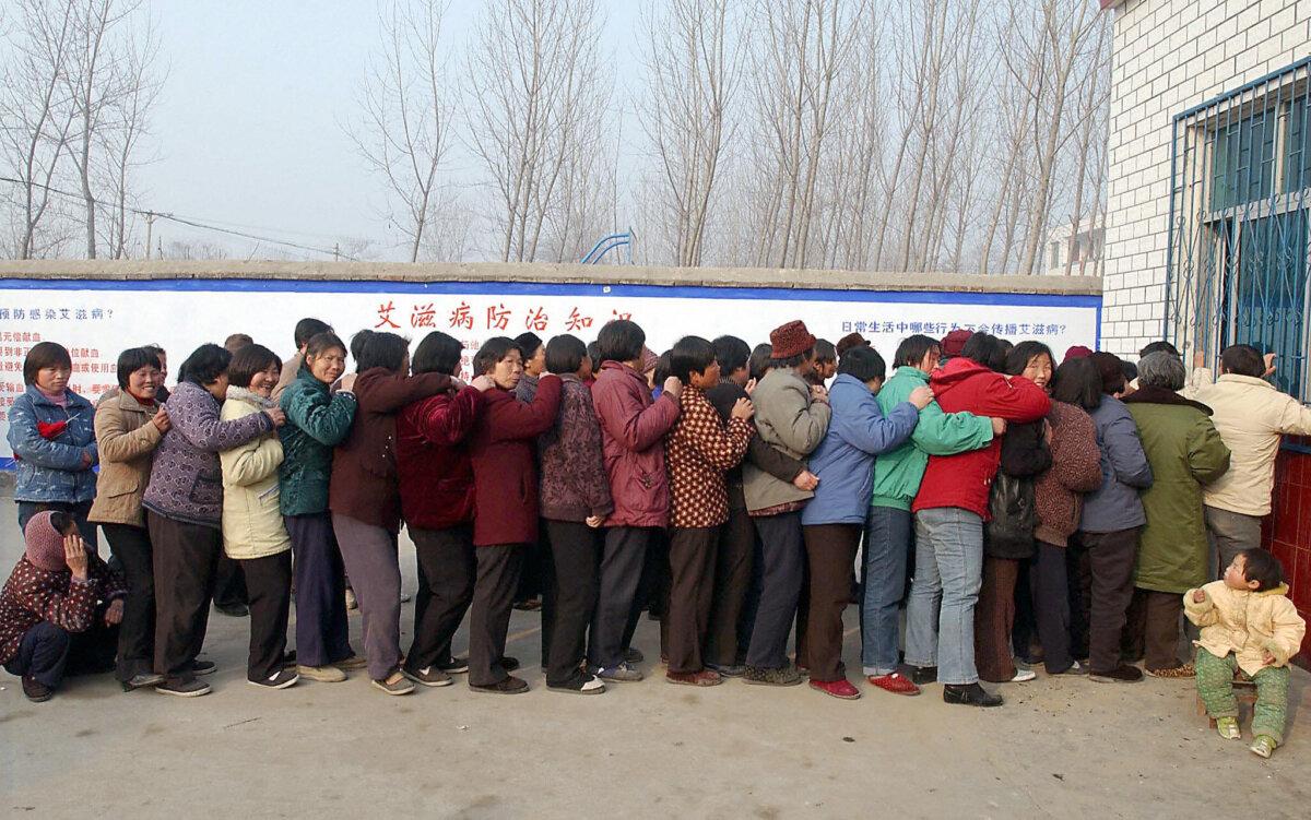  A group of Chinese farmers queue up at a local clinic to get their supply of free AIDS medication in Wenlou village, China's Henan province, on Feb. 21, 2004. (STR/AFP via Getty Images)
