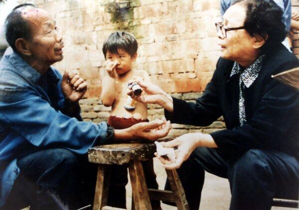 This undated photo shows retired doctor Gao Yaojie, 74, (R) applying medicine to a villager's arm as she helps people from neglected AIDS villages in the central China province of Henan. (STR/AFP via Getty Images)