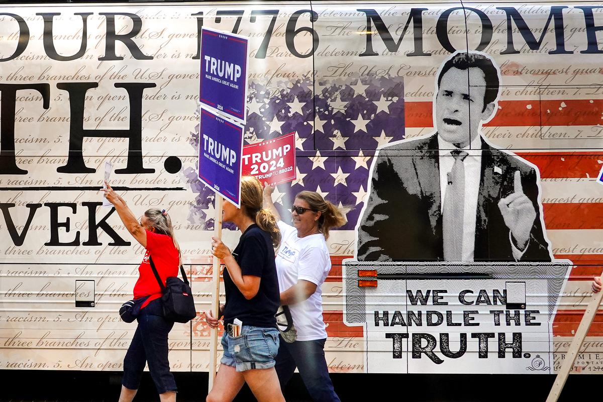 Supporters of former President Donald Trump carry signs past a campaign bus of Republican presidential candidate businessman Vivek Ramaswamy in Milwaukee, Wis., on Aug. 22, 2023. (Scott Olson/Getty Images)