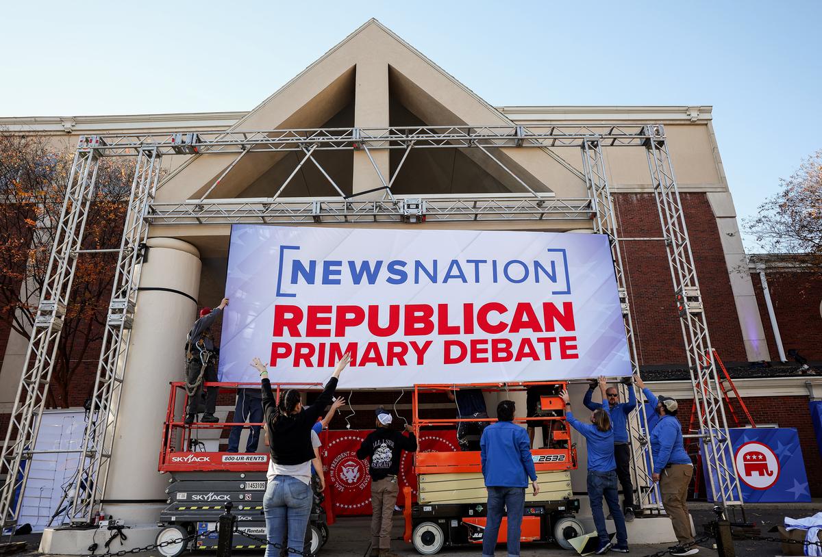 Workers install a banner at the University of Alabama ahead of the fourth Republican presidential debate in Tuscaloosa, Ala., on Dec. 5, 2023. (JIM WATSON/AFP via Getty Images)