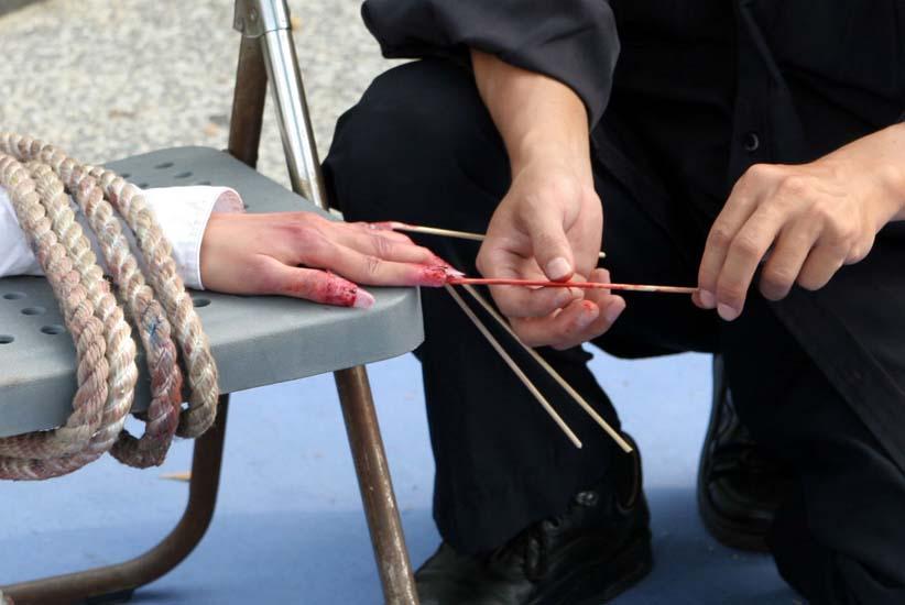 Reenactment of toothpicks pierced under nails. (Courtesy of Minghui.org)