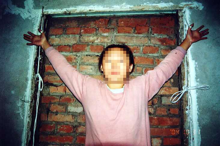 Reenactment of torture by being suspended with a rope tied around the thumbs. (Courtesy of Minghui.org)